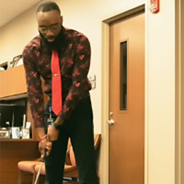 VCOM-Auburn’s director for diversity, equity and inclusion, minority recruitment and admissions coordinator demonstrates the campus’s new miniature golf course..