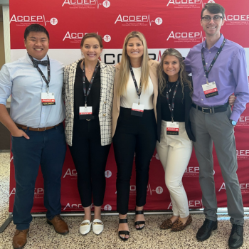 VCOM Louisiana students stand in front of ACOEP step and repeat