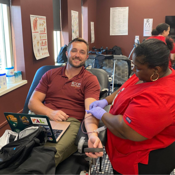 Student smiles while seated and getting his blood drawn