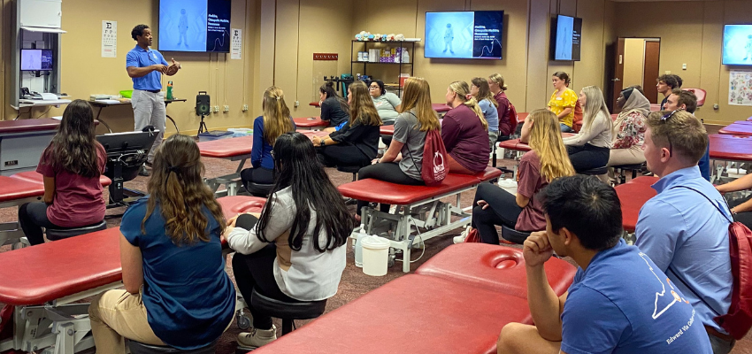 Students sitting at OMM tables listen to lecture