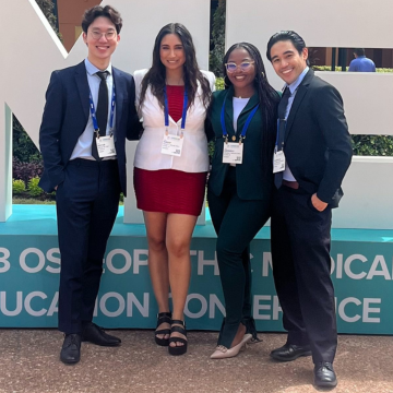 Four students standing in front of OMED signage