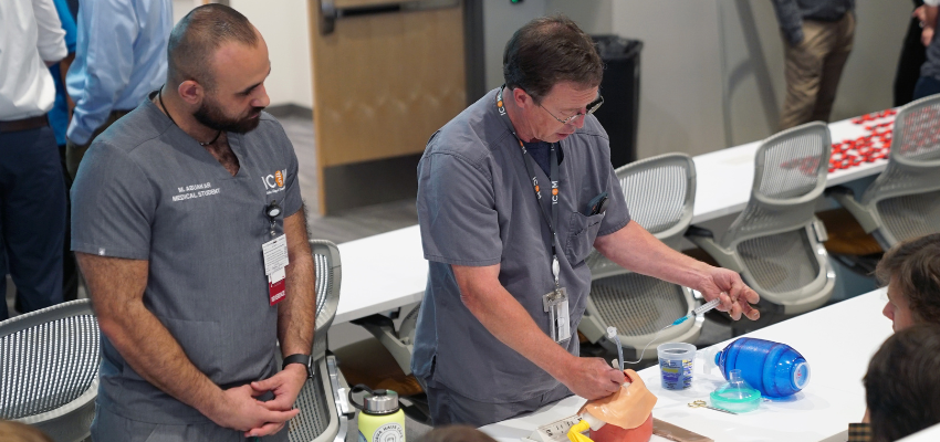 Students watch professor perform intubation on medical manikin