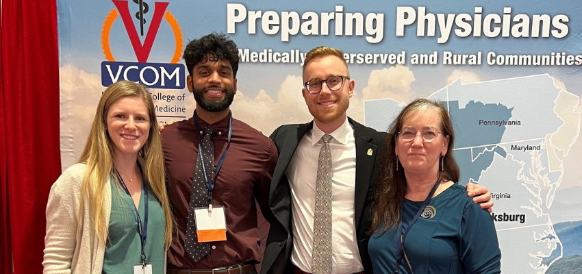 Three students and professor stand in front of their poster