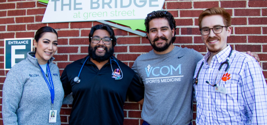 Four students standing in front of The Bridge at Green Street building