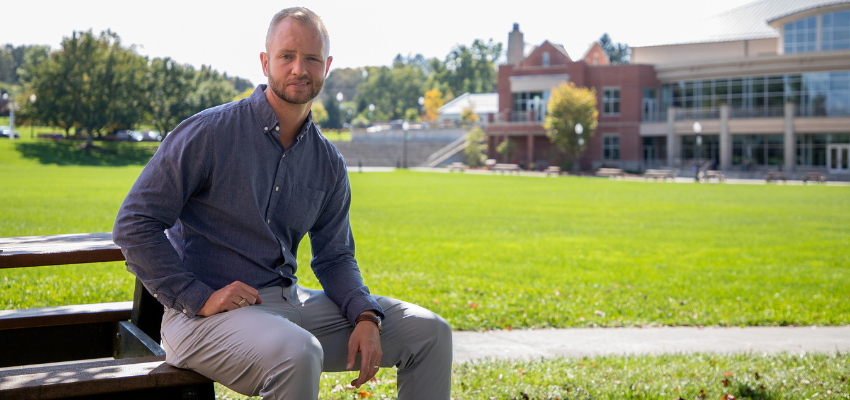 Dr. Plankey sitting with the WVSOM campus in the background