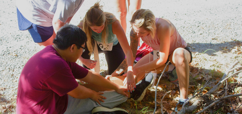 Students assist medical actor who has broken a leg