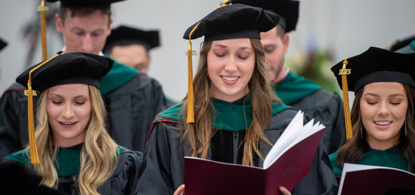 PCOM Georgia graduates read commencement pamphlets