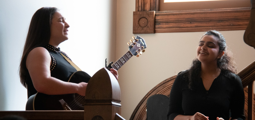 Two female students singing and playing guitar