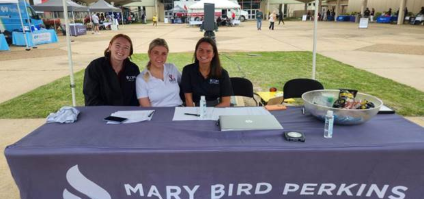 VCOM Louisiana students sit at table, welcoming others for cancer screenings