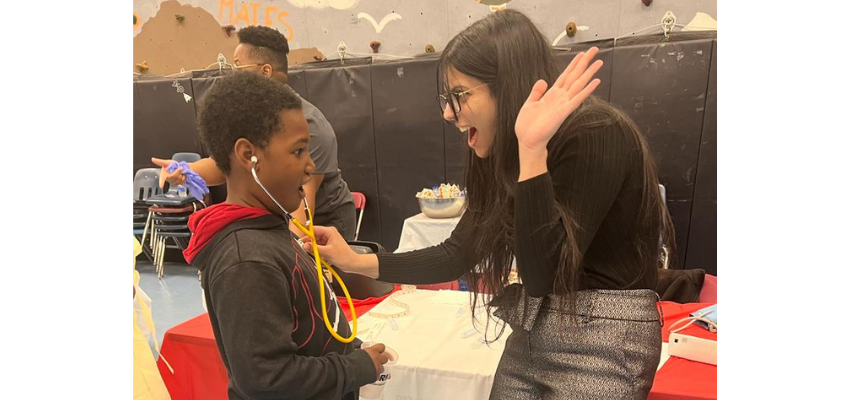 Student teaches child how to use stethoscope