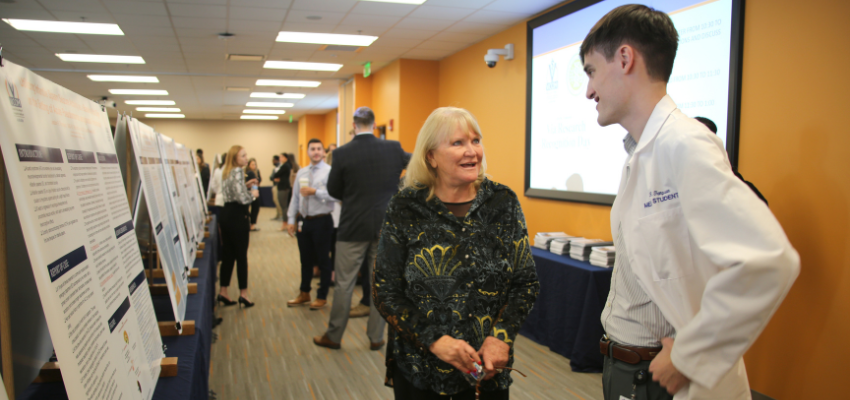 Medical student explains his poster research to his dean