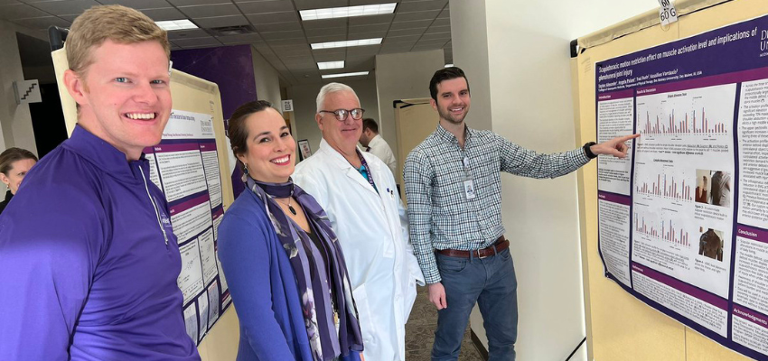 DMUCOM students present poster to faculty