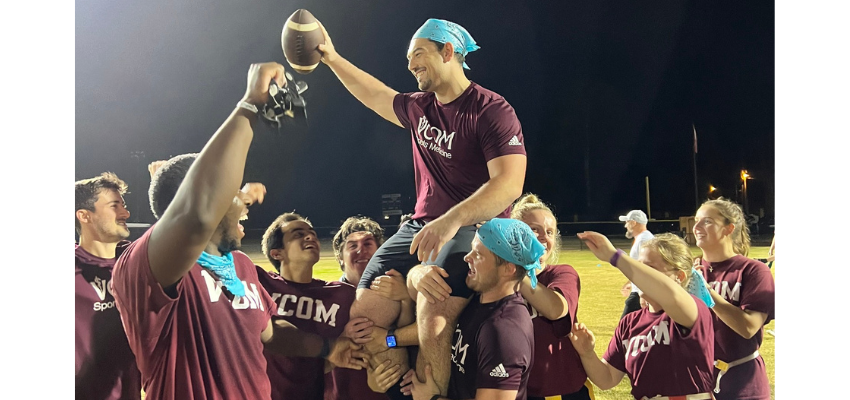Team hoists up fellow medical student holding a football