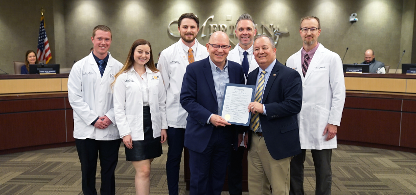 ICOM leadership holding commemorative certificate with students standing behind