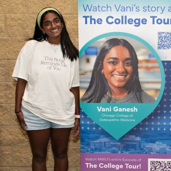 Medical student standing next to a banner with her photo, promoting