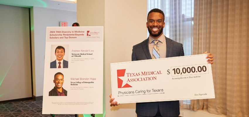A scholarship recipient holds a large ceremonial check from the Texas Medical Association.
