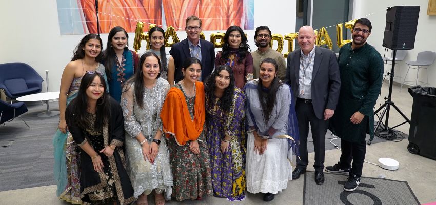 A group photo of students and faculty celebrating in traditional cultural attire at an event.