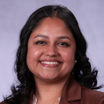 A headshot of a smiling individual in professional attire.