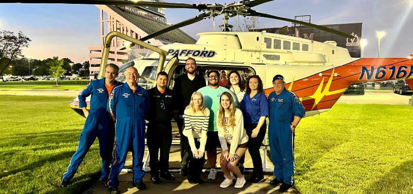 A group photo of medical students and helicopter pilots posing in front of a helicopter, showcasing an emergency medical or aviation-related experience.