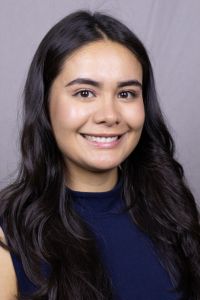 A woman smiles in a professional headshot against a neutral studio background.