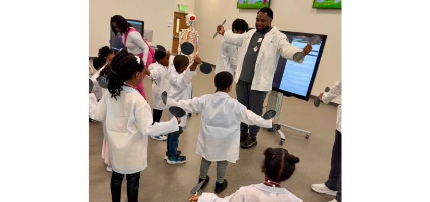 A medical student gets young students standing and exercising