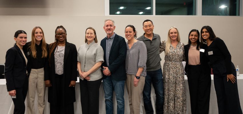 A group of faculty and staff stand together indoors, smiling for a group photo at an event.