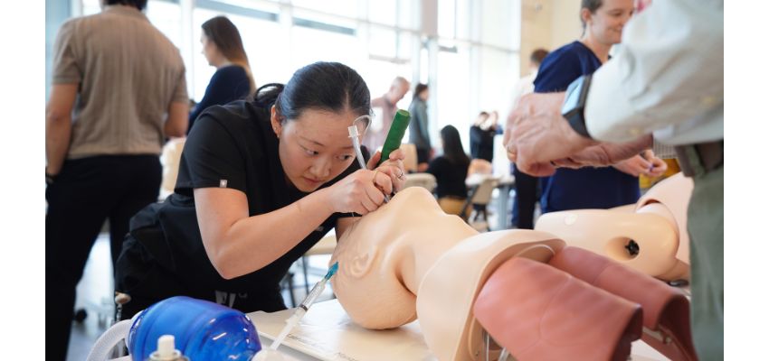 A student practices an airway procedure on a medical mannequin during a hands-on simulation training.