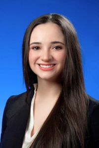 A woman smiles in a professional headshot against a blue studio background.