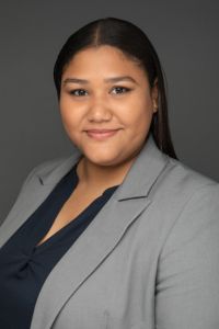 A woman in business attire smiles in a professional headshot against a dark background.