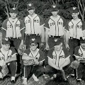 Ablack-and-whitephotoshowsavintagebaseballteamposingtogetherinuniformsonafield