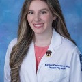 Astudentphysicianinawhitecoatsmilesinaprofessionalheadshotagainstabluebackground