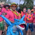 Agroupofpeopledressedincolorfultropical-themedoutfitsposetogetheroutdoorssomeholdinginflatablebeachitems