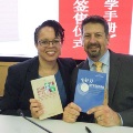 TwoindividualsseatedatatableholdbooksduringaneventfeaturingChinese-languagematerialsandpresentationslides
