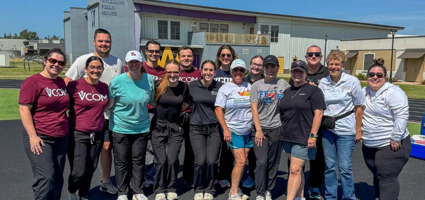 A group of people poses together outdoors on a track during a community or wellness event.