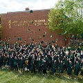 GraduatesincapsandgownstosstheirhatsintheairoutsidetheWestVirginiaSchoolofOsteopathicMedicinebuilding