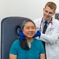 Astudentphysicianexaminesaseatedpatientsneckinaclinicalexamroom