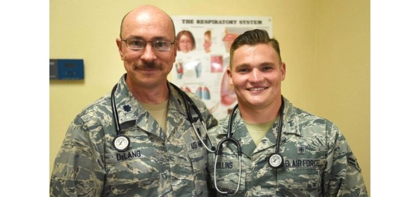 Two U.S. Air Force medical personnel wearing uniforms and stethoscopes pose together indoors.