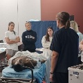 Agroupofstudentsparticipatesinamedicalsimulationtrainingsessionaroundapatientmannequininaclassroom
