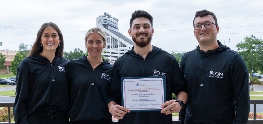 Four VCOM Sports Medicine students pose together outdoors, with one student holding a certificate.