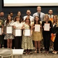 Studentsandfacultyposetogetherindoorswhileholdingcertificatesandawardsduringarecognitionceremony