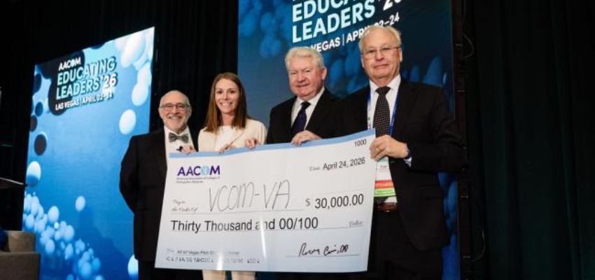 Three individuals stand on stage holding a ceremonial check for $30,000 during AACOM’s Educating Leaders conference in Las Vegas.