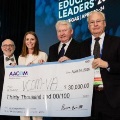 Threeindividualsstandonstageholdingaceremonialcheckfor30000duringAACOMsEducatingLeadersconferenceinLasVegas