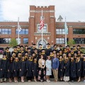 AgroupofgraduatesincapsandgownsposesonthestepsoutsideacampusbuildingattheWestVirginiaSchoolofOsteopathicMedicine