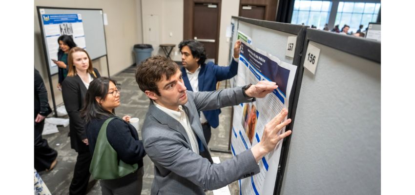 Students and faculty members review and mount research posters during a poster presentation event.