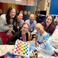 Medicalstudentsandhealthcarestaffgatheraroundapediatricpatientinahospitalroomsmilingtogetherduringavisit