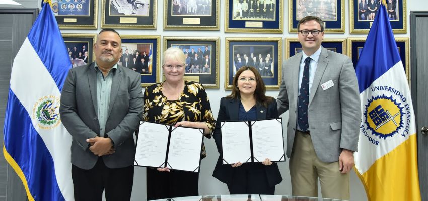 Representatives from two institutions display signed partnership documents during a formal agreement ceremony.