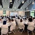 Medicalstudentsinwhitecoatsattendanorientationoreducationalsessioninaclassroomwhileaspeakerpresentsatthefrontoftheroom