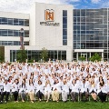 NoordaCollegeofOsteopathicMedicinestudentsinwhitecoatsgatherforaclassphotoinfrontofthecollegebuilding