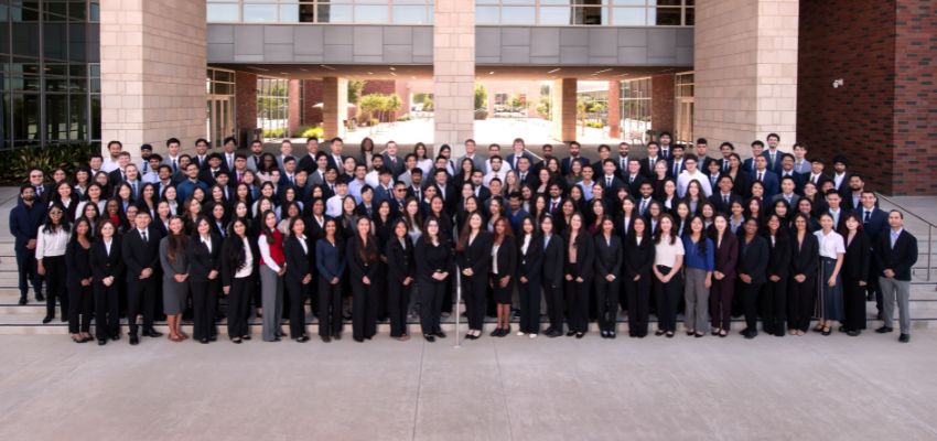 Large group of CHSU-COM students dressed in professional attire posing outside the college building.