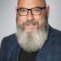 PortraitofaTCOMfacultyorstaffmemberwithalonggraybeardwearingglassesandablueplaidblazer